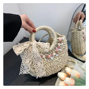 Dettaglio borsa in paglia tessuta a mano con fiocco in pizzo e fiori 3D per spiaggia
