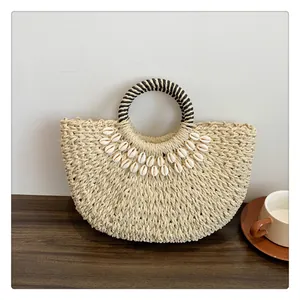 Detailansicht der gewebten Strohtasche mit weißen Muschelakzenten und zweifarbigem Griff