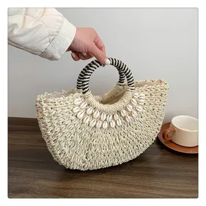 Nahaufnahme der Stroh-Handtasche mit Muschel-Dekor und gestreiftem Griff