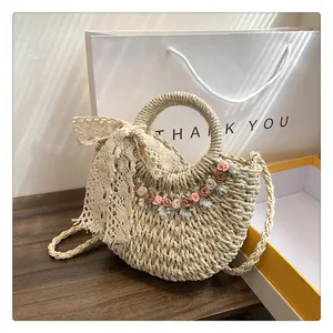 Dettaglio borsa in paglia intrecciata a mano con fiori e un fiocco in pizzo