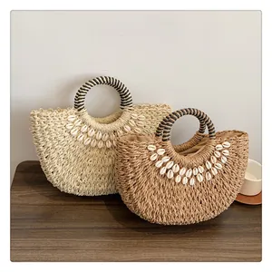 Details der Strohhandtasche mit Muschelbesatz und kontrastierenden runden Griffen
