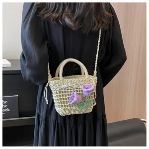Detail of handwoven straw bucket bag with purple floral decor and 'Good day' embroidery