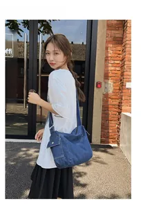 Outdoor shot of a deep blue denim tote bag with adjustable strap and cargo pocket detail
