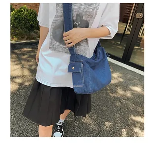 Detail of blue denim saddle bag featuring a functional side cargo pocket with metal snap button