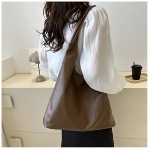 Detail view of large dark brown leather tote bag with stylish strap label and soft texture