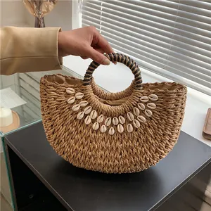 Handgefertigte Strohtasche mit Muscheln und runden Griffen für den Strandurlaub am Meer