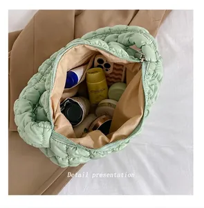 Spacious interior of light green quilted puffy bag showing storage for umbrella and phone