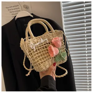 Close-up of handmade straw bag featuring crochet pink flowers and Good Day embroidery