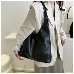 Close-up of a black leather hobo bag with natural folds and a small white woven label