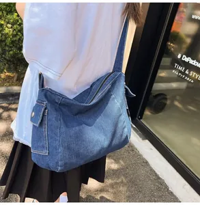 Detail of dark blue denim tote bag featuring side flap pocket and wide shoulder strap