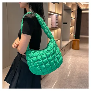 Side view of model wearing a bright green quilted puffy hobo bag with wide shoulder strap