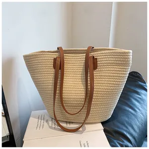 Detail of hand-woven straw tote bag with brown faux leather handles for summer vacation