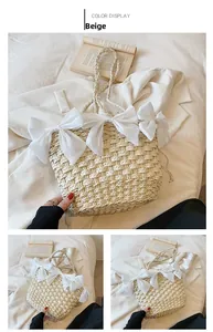 Détail du sac en paille beige avec trois nœuds en organza blanc et texture tissée