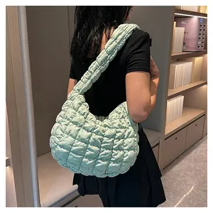 Close-up of light green quilted puffy shoulder bag showing soft pleated texture on a model