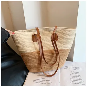 Detailed close-up of large straw tote bag featuring contrast stitching and leather handles