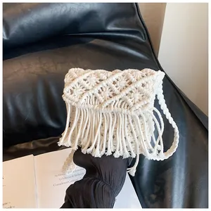 Close-up of white handmade woven straw bag with diamond pattern and long tassel details