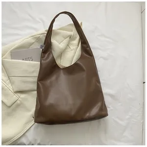 Top view of deep brown faux leather hobo tote bag with brand label on white fabric