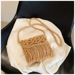 Detail of khaki woven crossbody bag featuring diamond hollow patterns and long tassels