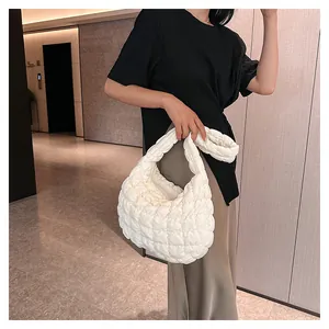 Detailed close-up of white quilted bubble hobo bag with soft pleated texture on wide strap