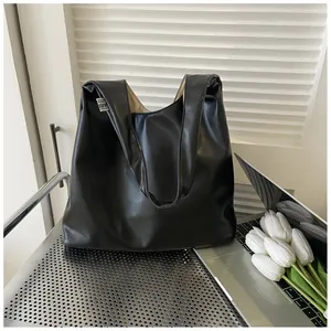 Detail of minimalist black tote bag with side woven label next to white tulips