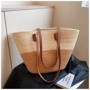 Detail of dual-tone straw tote bag with brown leather straps on a black leather jacket