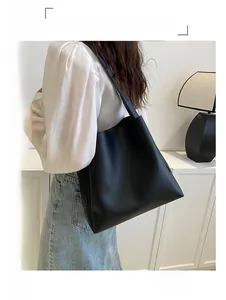 Side view of large black leather tote bag worn as a shoulder bag on a model
