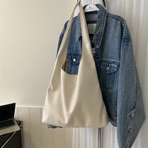 Detail of off-white large capacity tote bag hung with a denim jacket background