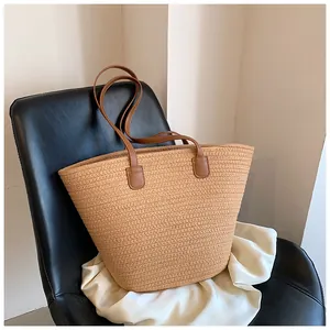 Detailed view of the woven straw tote bag texture with brown leather handles
