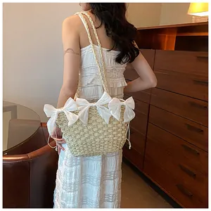 Détail du sac bandoulière en paille avec grands nœuds en satin blanc pour l'été