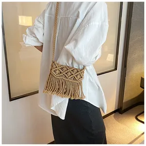 Detail of bohemian straw crossbody bag with geometric weave pattern and long tassels