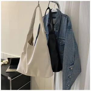 Close-up of cream and black large capacity hobo tote bags with logo tags on a hanger