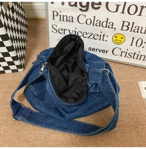 Detail of blue denim tote bag showing metal zipper closure and soft black inner lining