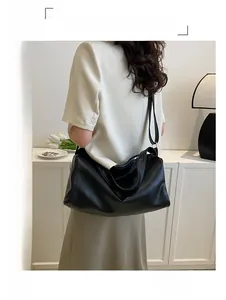 Gros plan détaillé du sac hobo en cuir texturé noir avec bandoulière réglable sur modèle