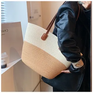 Detailed side view of a large woven tote bag with contrast stitching and leather handles