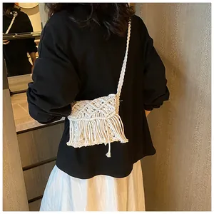 Bohemian off-white macrame crossbody bag with long tassels shown on shoulder
