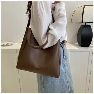 Brown matte tote bag shown on model in a minimalist interior for casual outfit styling