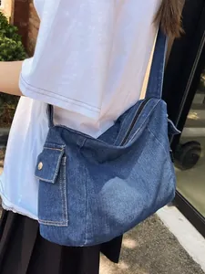 Deep blue denim tote bag with wide shoulder strap and side pocket in outdoor natural light