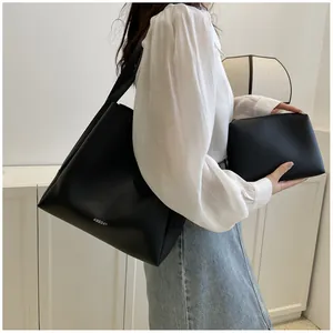 Detail of minimalist black leather tote bag set with branded logo and small clutch