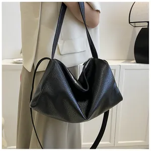 Détail d'un sac bandoulière noir avec texture en cuir craquelé et fermeture éclair argentée