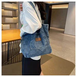 Detail of vintage denim tote bag showing brown leather patch and large front pocket