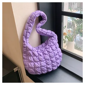 Close-up of purple quilted puffer shoulder bag with soft textured puffy fabric and zipper