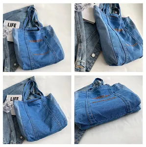 Detail view of dark blue denim tote bag with vibrant orange embroidery and sturdy stitching