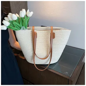 Close-up of large straw tote bag with brown leather handles and woven texture details