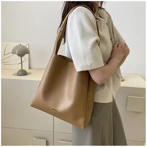 Close-up of the AIBEIDA brand logo embossed on a brown vintage leather tote bag