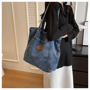 Detailed view of vintage denim tote bag with brown leather patch and large front pocket