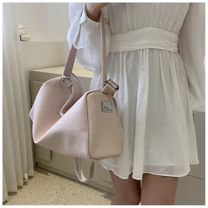 Détail d'un sac à main en cuir texturé rose clair avec ornements métalliques