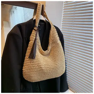 Detailed close-up of beige straw woven shoulder bag with vintage tassel ornament