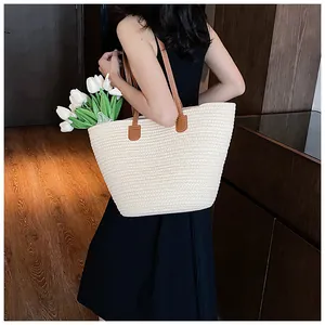 Detail of handwoven straw tote bag with brown leather straps and tulip decoration