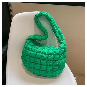 Detail of green quilted puffer shoulder bag with bubble texture on a white chair