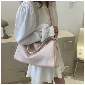 Détail de sac bandoulière rose clair avec texture cuir grainé sur photo modèle épurée